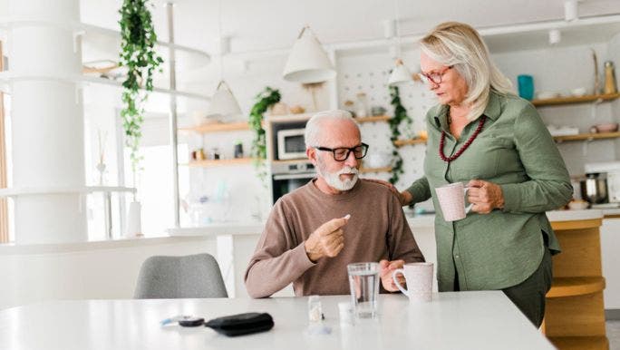 A senior couple are taking probiotics supplement in a kitchen