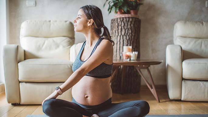 A woman stretching her back on a mat on the floor wonders whether the pelvic floor is linked to lower back pain.