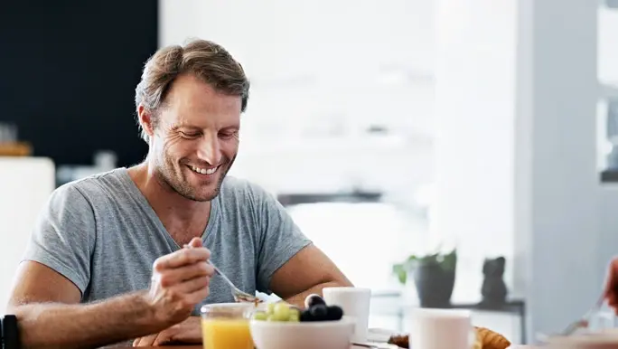relaxed man at home eating a healthy breakfast of magnesium rich whole grain muesli
