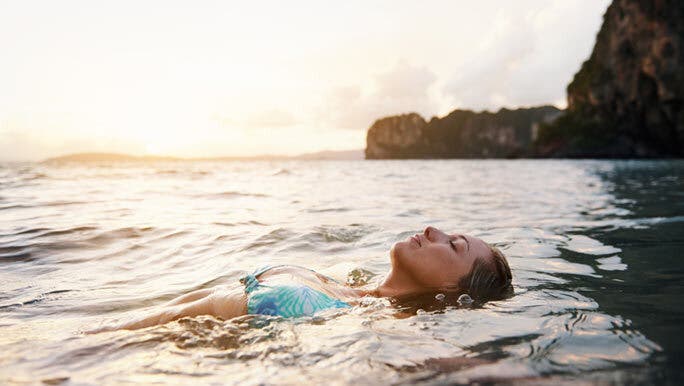 Relaxed woman floating on her back in the ocean at sunrise