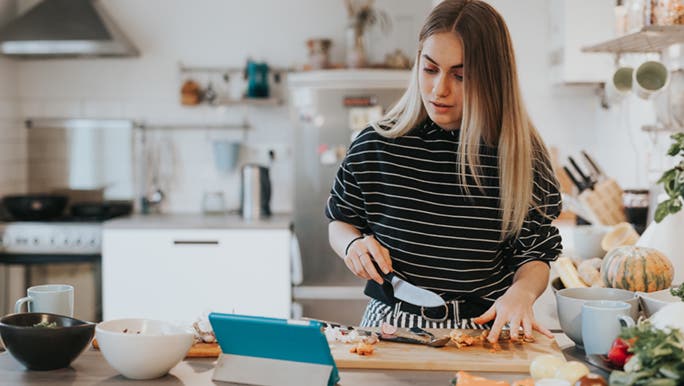 A woman is cooking in a bright, industrial-style kitchen, she is following a recipe her nutritionist gave her. 