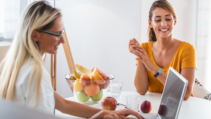 A female dietician and a young woman discuss how many carbs to eat before a workout.