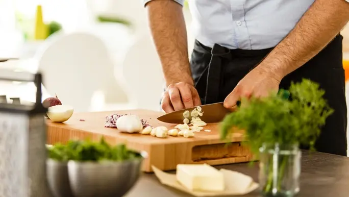 Man chopping garlic cloves a high FODMAP food