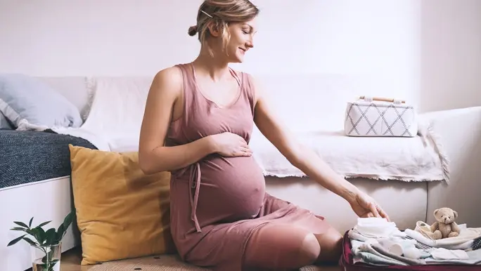 Pregnant woman packing her hospital bag and ticking off items on a list