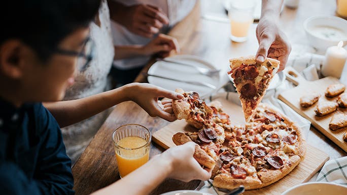 A family enjoys pepperoni pizza. 