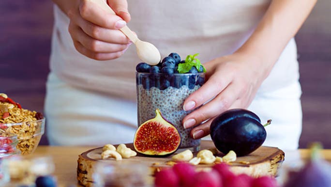 A close-up image of a woman’s hands scooping berries, which are good for gut health, out of a container