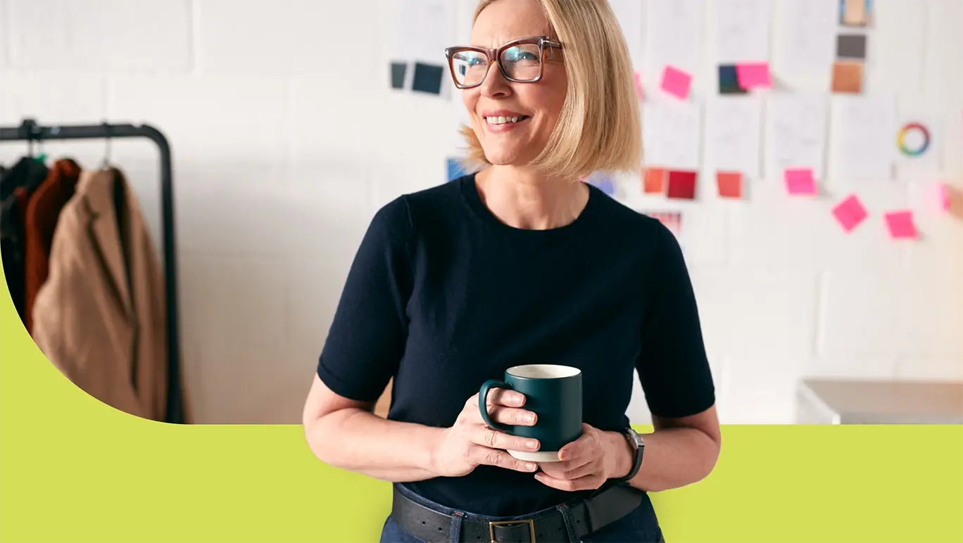 Mature woman smiling slightly in her workplace enjoying a coffee