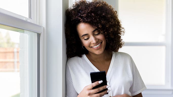 A pregnant woman is looking at her phone and smiling. She has just clarified that pregnant women can eat bacon. 