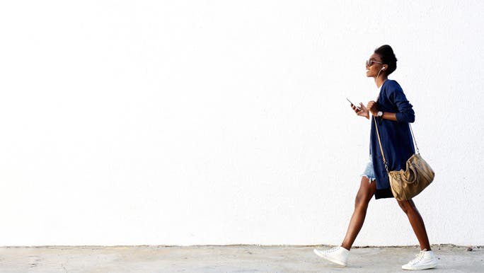 Young woman walking to work listening to music