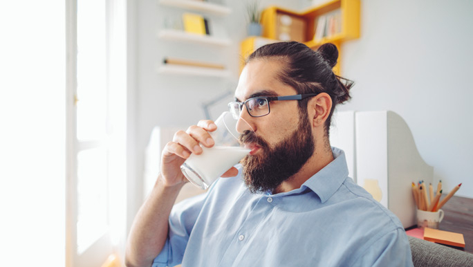 Bearded man drinking a glass of milk at home