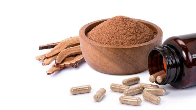 Mushroom powder is displayed in a wooden bowl with mushroom powder capsules and mushrooms displayed on a table