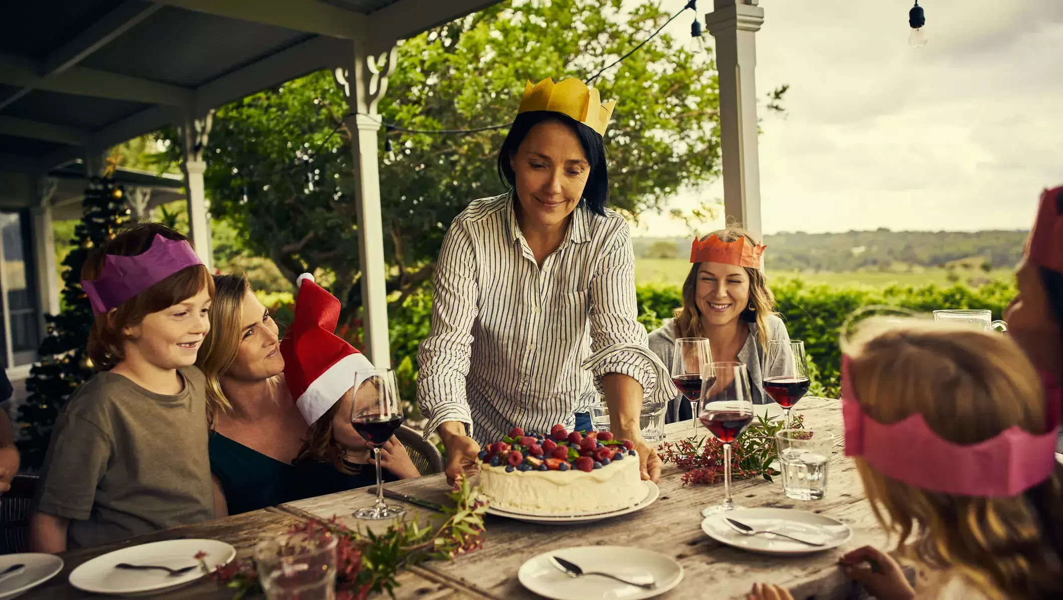 Woman serving a low FODMAP pavlova topped with lactose free cream and berries to her family at Christmas lunch