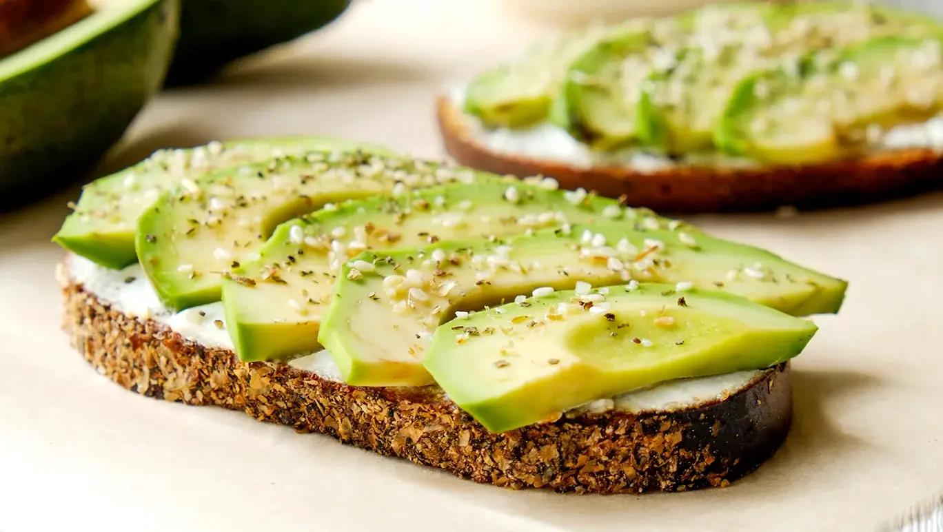 Piece of avocado on toast sprinkled with sesame seeds.
