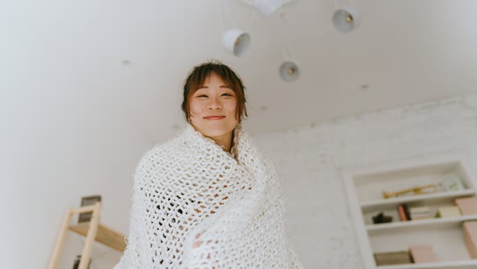 Happy young woman wrapped in a white weighted blanket