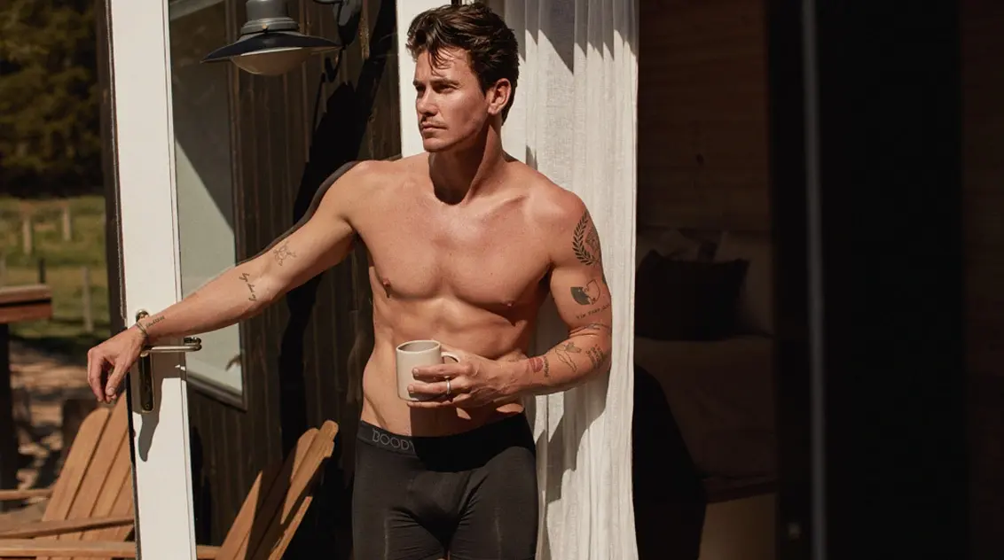 A man posing in Boody Men's Everyday Boxers drinking a cup of coffee