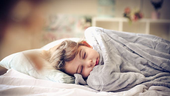 A child snoozes under a weighted blanket. 