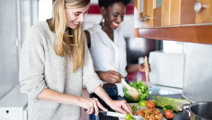 Two female friends preparing vegetables in the kitchen