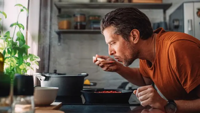 Man in the kitchen tasting as he cooks a meal made with pantry staples