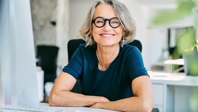 Smiling, confident middle age woman sitting at her work desk 