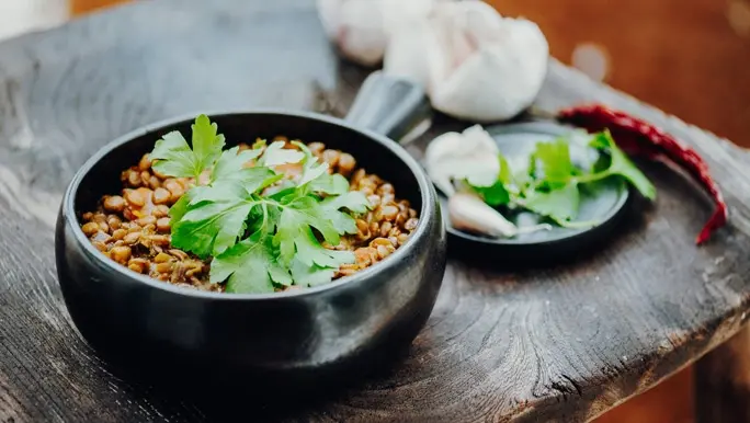 Lentil dahl in a black bowl topped with fresh coriander