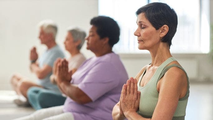 A group of people are sitting on the floor in a line practising meditation