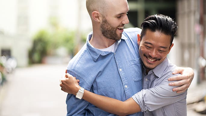 A couple cuddles in the street and smiles. 