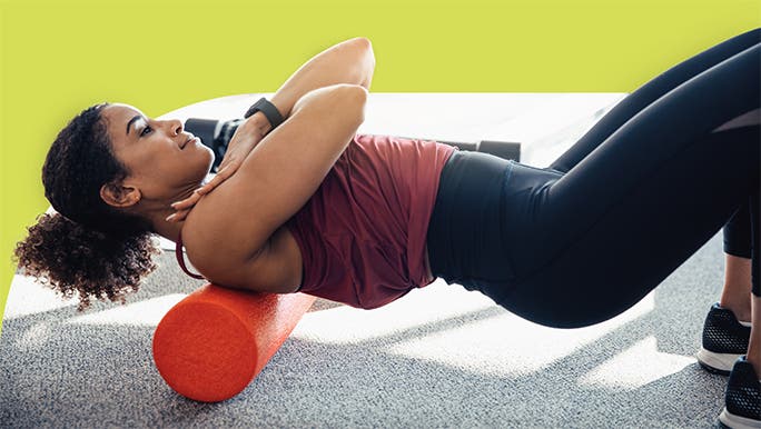 Woman in active wear rolling out her back and shoulders on a foam roller