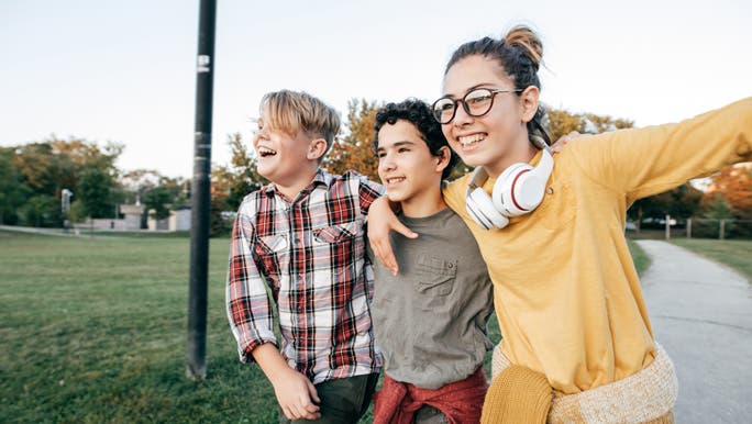 3 happy teenage friends hanging out together in the park