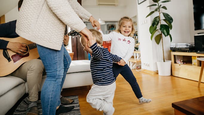 A family is dancing in their home, dad is playing the guitar. Music and health are so closely related. 