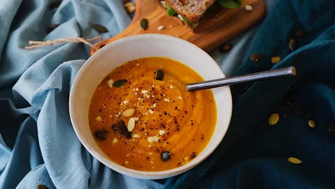 Roast pumpkin soup in a white bowl sprinkled with pumpkin seeds