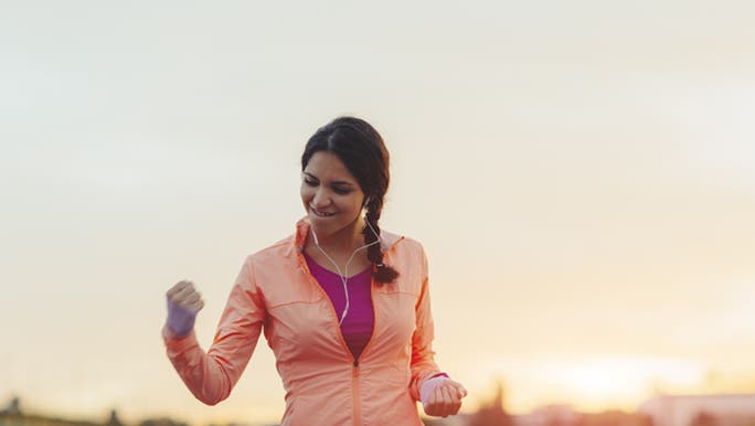 A woman smiles looking proud as she flexes her bicep muscles and knows that HIIT exercise doesn’t have to make you lose muscle.