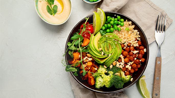 Top view of a bowl of mixed grilled vegetables on a light background with squeezed limes scattered around. Brain healthy foods galore!