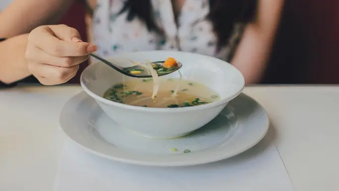 A woman eating a bowl on instant miso soup