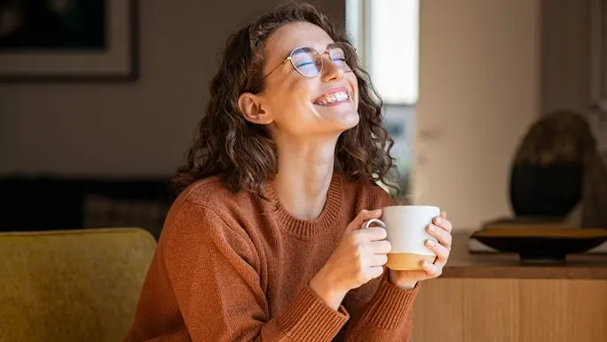 Smiling pretty girl drinking hot tea in front of the window in winter.