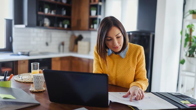 A woman works from a desk in her home, she looks happy and productive.