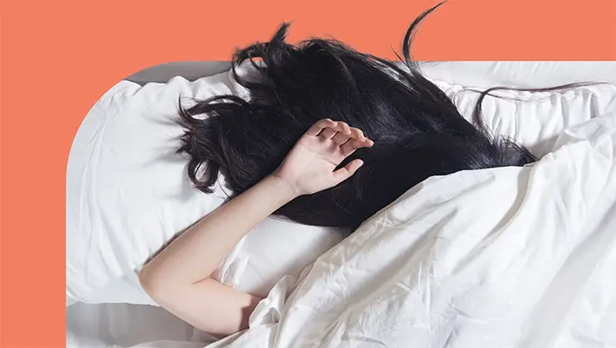 Woman fast asleep under a white sheet, only her black hair and one arm is showing.
