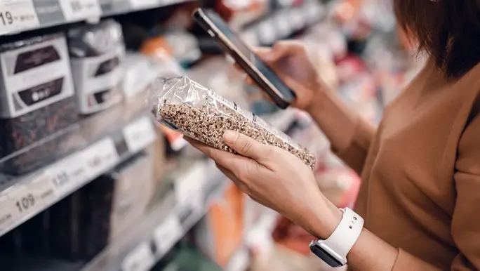 Woman in a supermarket reading a label on a packet of quinoa