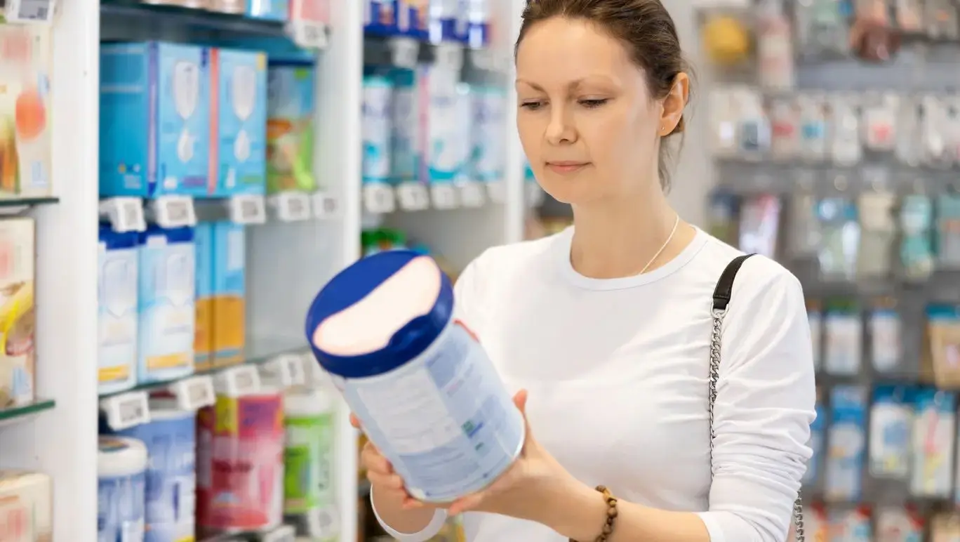 Women reading a baby formula tin