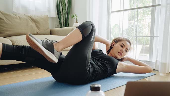 A pregnant woman stretches on a mat on the floor and wonders whether pilates is good for pelvic floor muscles. 