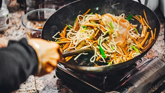Person cooking a stir fry in a wok