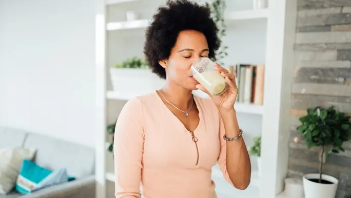 Woman in her kitchen drinking a collagen powder smoothie in the morning