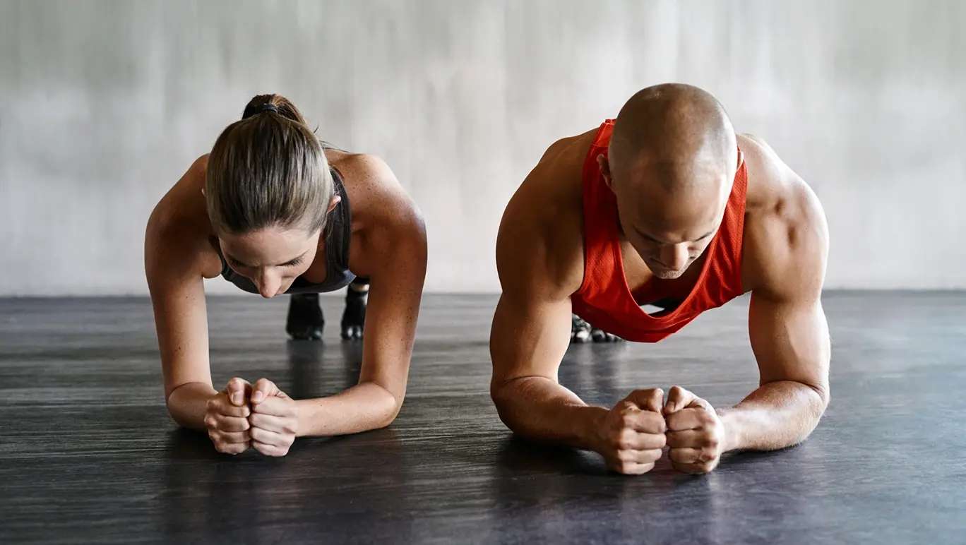 A woman and a man in the gym doing the plank