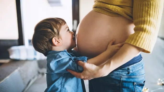Young boy hugging his mum and kissing her pregnant belly