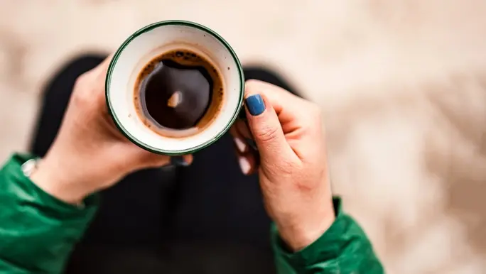 Above photo of coffee cup in woman's hands