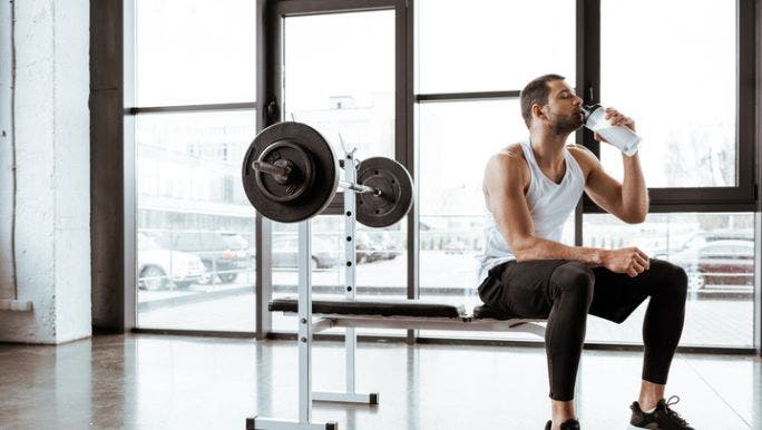 A man working out in a gym is drinking a protein shake