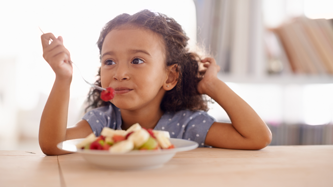 Girl eating a fruit salad made with low fodmap fruits