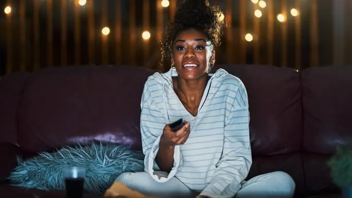 Woman staying up late and watching TV in her pyjamas