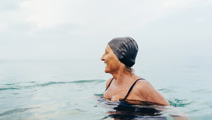 Mature woman in a black swimming cap and costume in the ocean