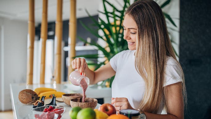 A woman stands in her kitchen preparing low tox food.