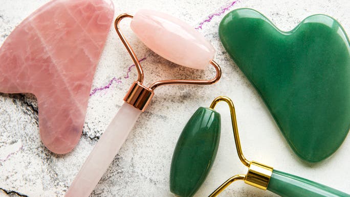 A flat lay showing rose quartz and jade face rollers